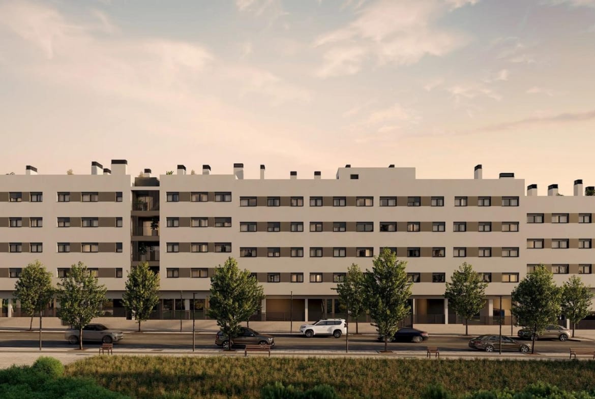Long apartment façade and tree-lined street at dusk in San Agustín, Alicante