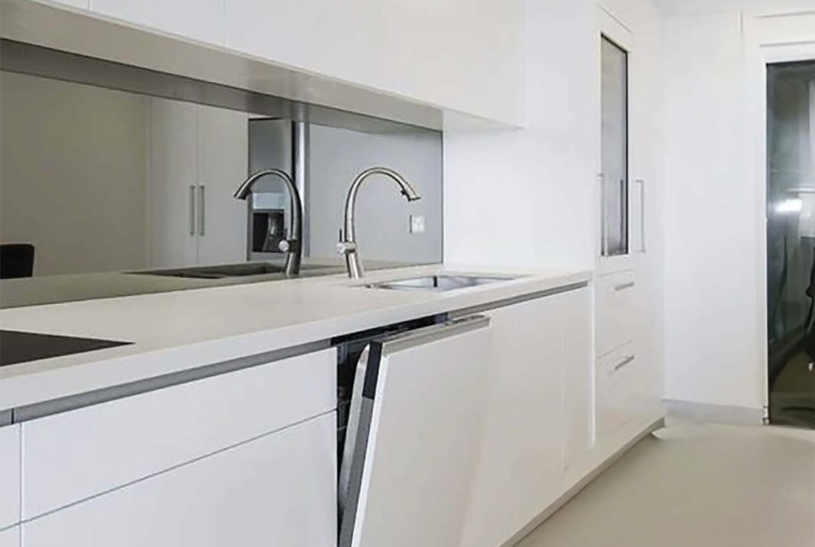 White kitchen with long worktops, fitted cabinets and a window in Relleu, Alicante