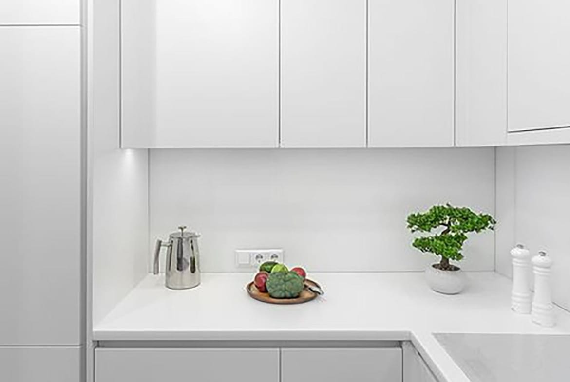 Kitchen corner with white cupboards, a pale worktop and a potted plant in Relleu, Alicante