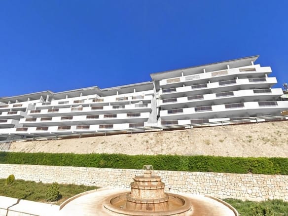 White apartment building with broad terraces above a stone retaining wall in Relleu, Alicante