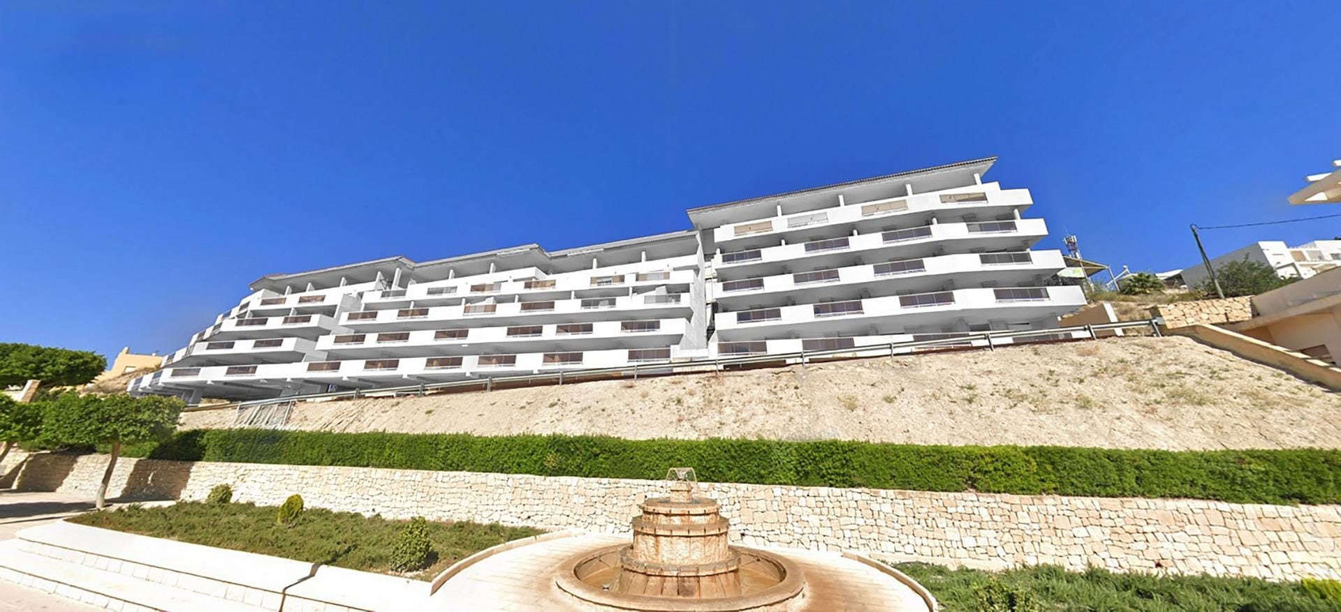 Residential complex in Relleu with communal swimming pool and open views White apartment building with broad terraces above a stone retaining wall in Relleu, Alicante