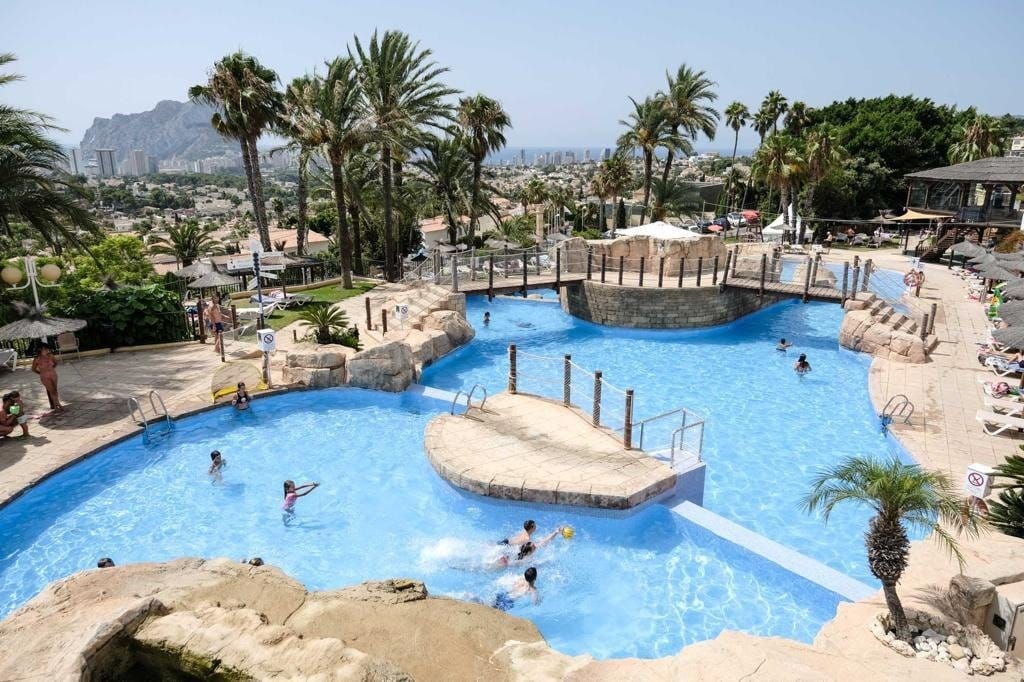 Communal swimming pool with a small island, palm trees and landscaped surroundings in Gran Sol, Calpe, Alicante