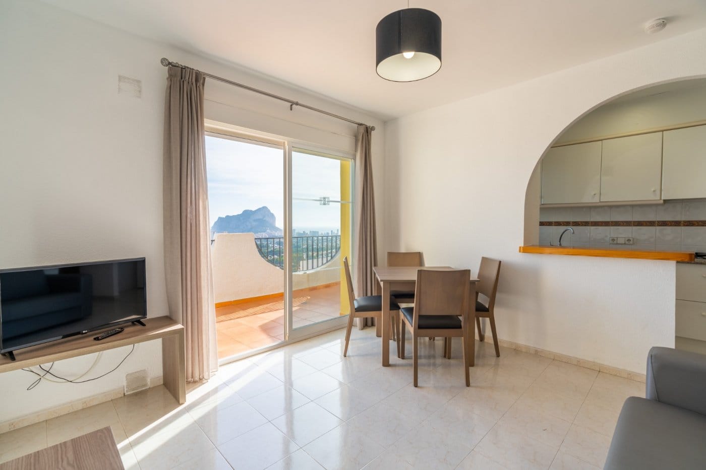 Dining area beside an arched kitchen opening and a terrace overlooking the sea in Gran Sol, Calpe, Alicante