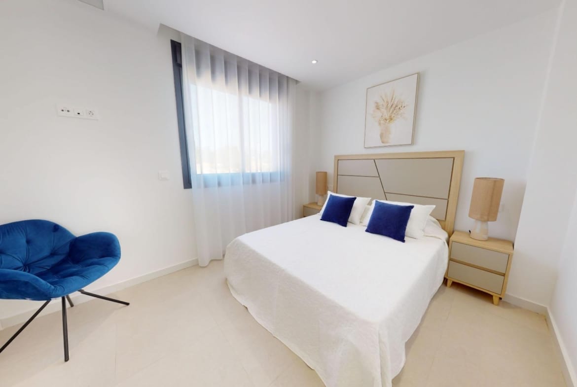 Example bedroom with a blue chair beside the bed in La Marina, San Fulgencio, Alicante