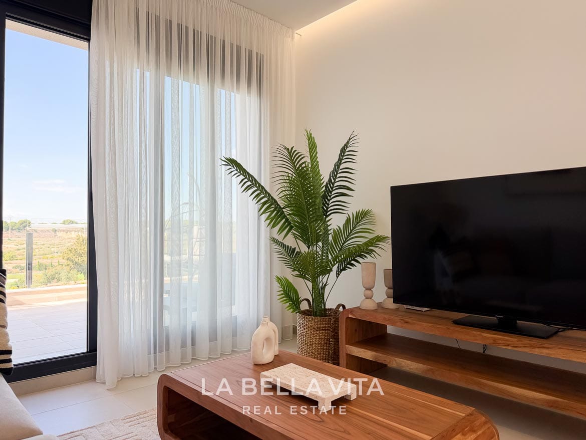 Modern Resale Apartment fot sale in Lo Romero Golf, Pilar de la Horadada, Alicante-11 Living room detail with sheer curtains, a potted plant and a wooden TV console beside the terrace