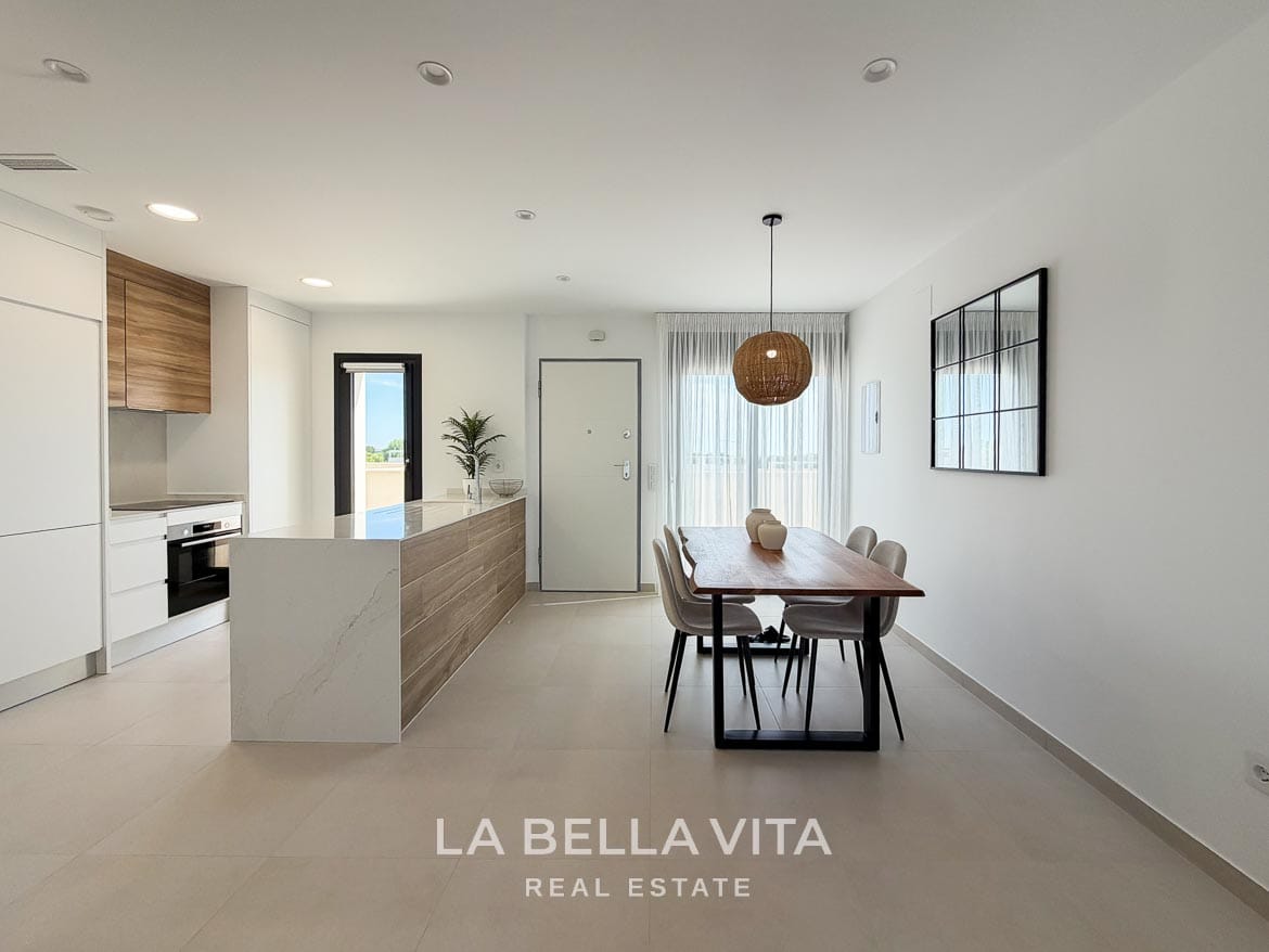 Modern Resale Apartment fot sale in Lo Romero Golf, Pilar de la Horadada, Alicante-12 White and wood-effect kitchen beside a dining table under a woven pendant light