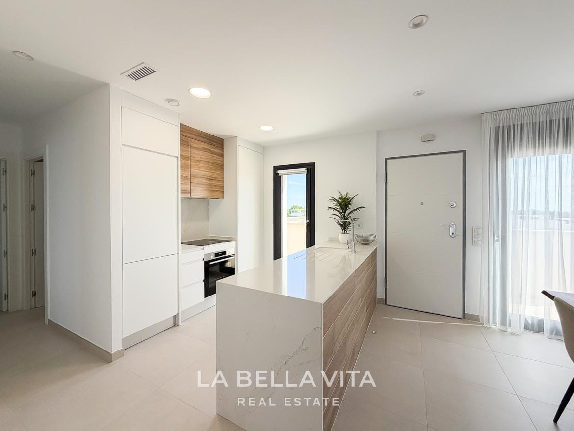 Modern Resale Apartment fot sale in Lo Romero Golf, Pilar de la Horadada, Alicante-17 Modern kitchen with white fitted cabinets, an oven and a long peninsula beside the entrance