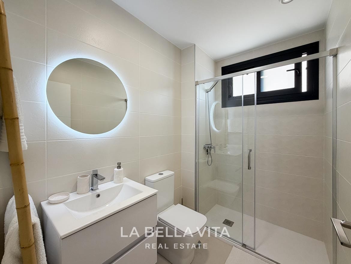 Modern Resale Apartment fot sale in Lo Romero Golf, Pilar de la Horadada, Alicante-22 Tiled bathroom with a glass shower enclosure, floating vanity and illuminated round mirror