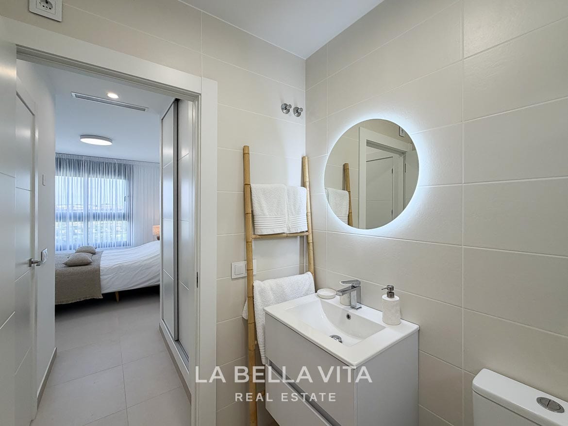 Modern Resale Apartment fot sale in Lo Romero Golf, Pilar de la Horadada, Alicante-23 En-suite bathroom vanity with a round illuminated mirror and a doorway to the double bedroom