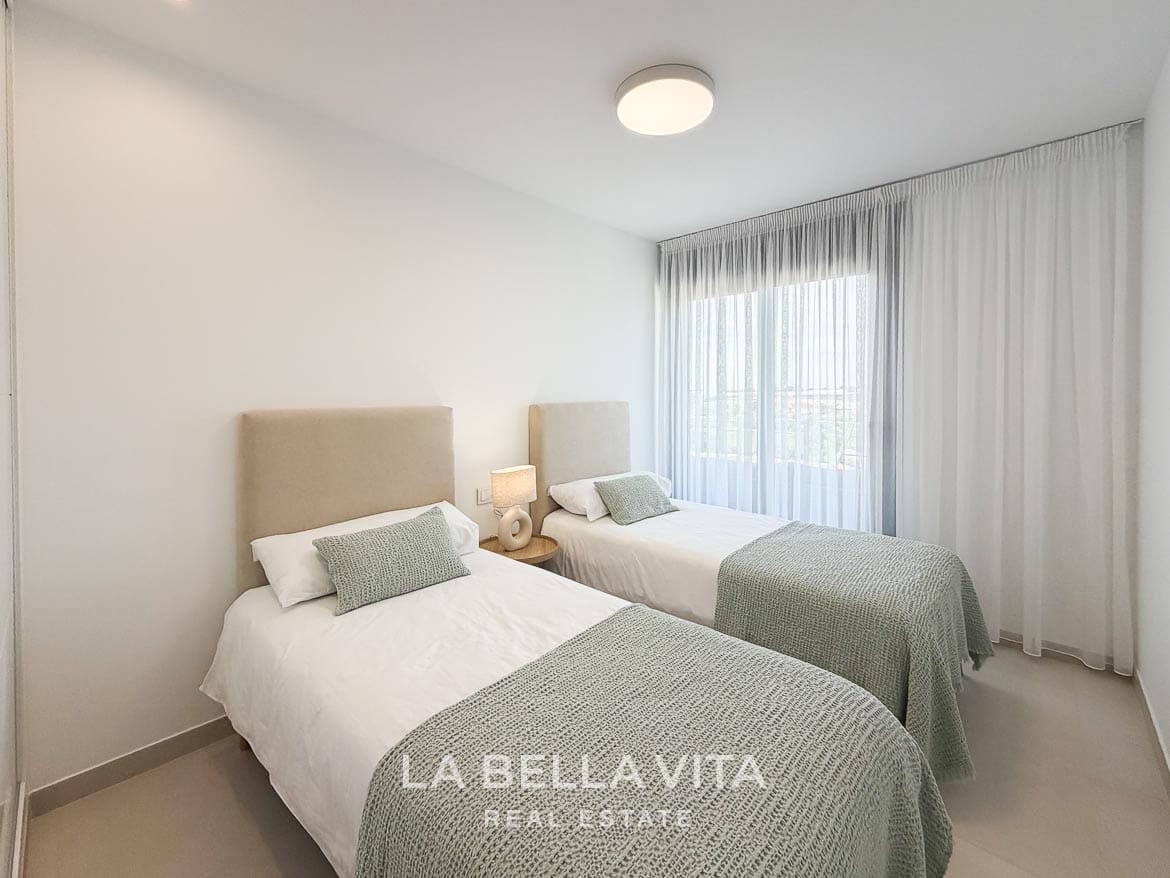Modern Resale Apartment fot sale in Lo Romero Golf, Pilar de la Horadada, Alicante-26 Twin bedroom with upholstered headboards, pale green throws and a large curtained window