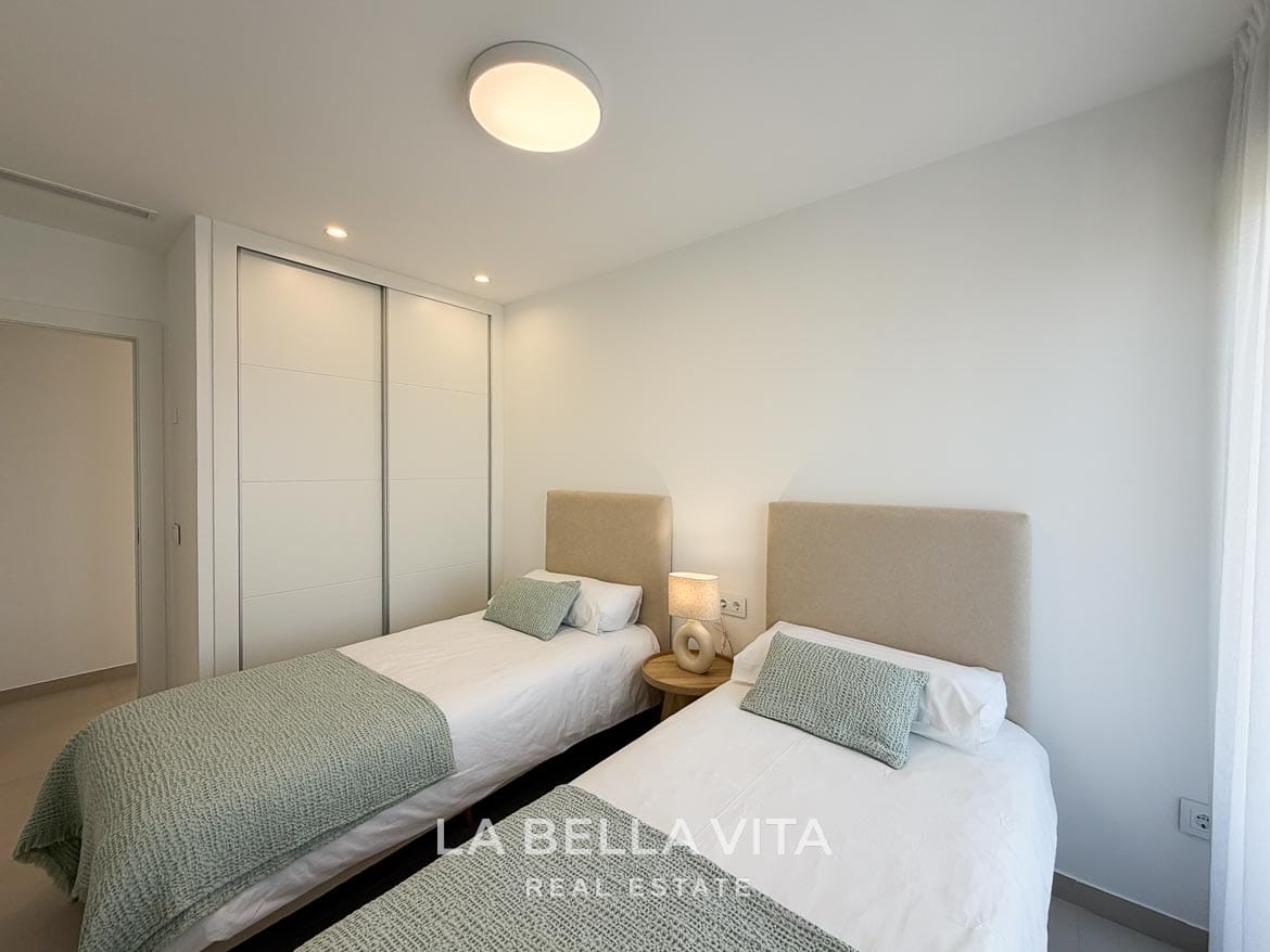Modern Resale Apartment fot sale in Lo Romero Golf, Pilar de la Horadada, Alicante-27 Twin beds beside a white fitted wardrobe with sliding doors in the second bedroom