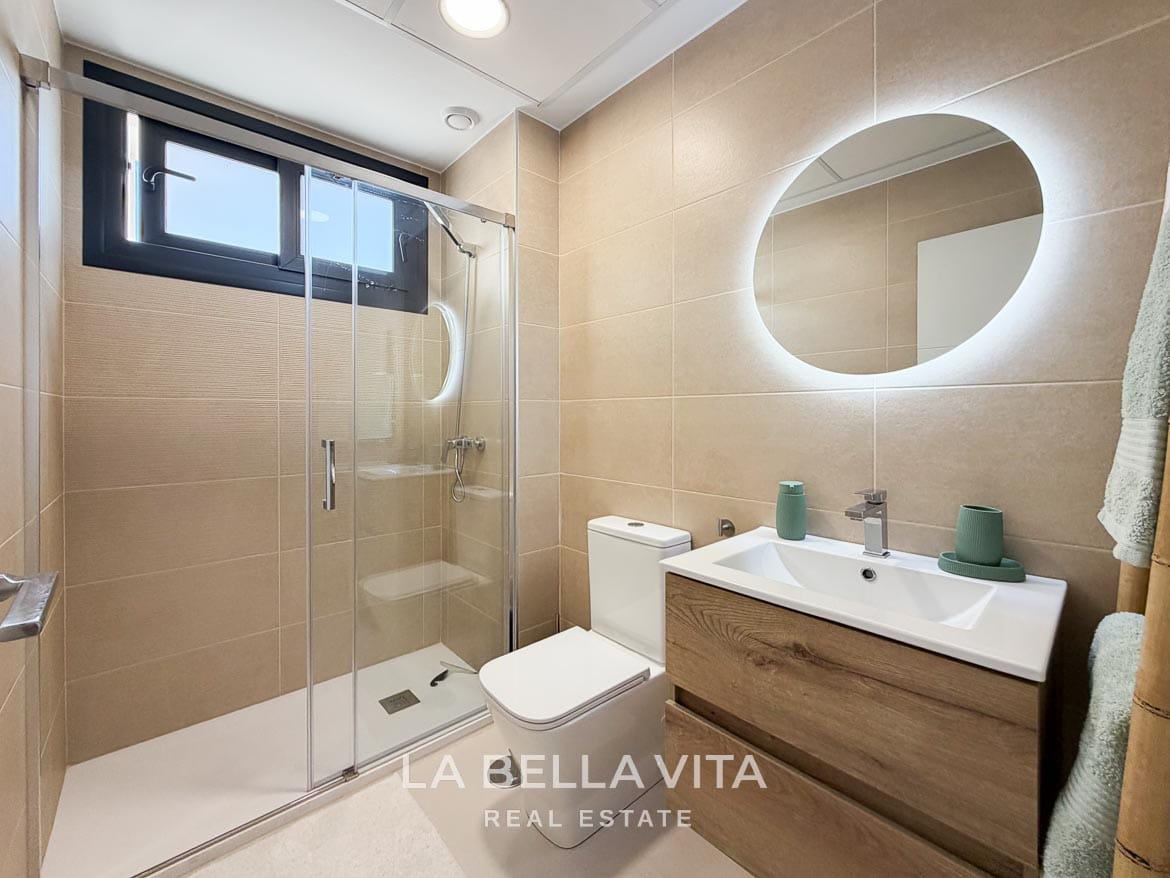 Modern Resale Apartment fot sale in Lo Romero Golf, Pilar de la Horadada, Alicante-29 Second bathroom with a wood-effect vanity, illuminated mirror and glass-enclosed shower