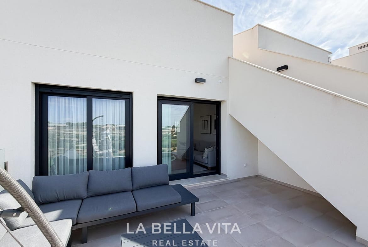 Tiled terrace with a grey outdoor sofa, sliding doors and stairs to the roof solarium