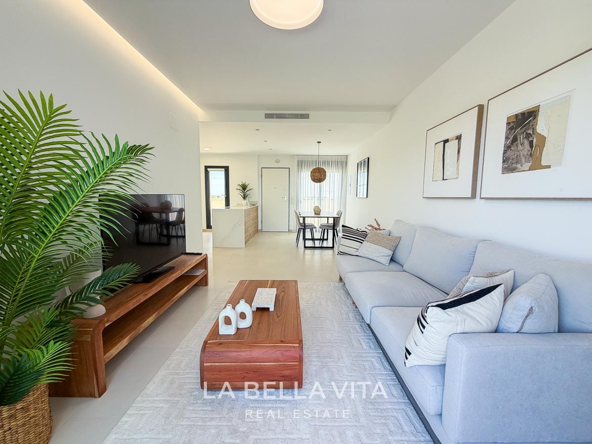 Modern Resale Apartment fot sale in Lo Romero Golf, Pilar de la Horadada, Alicante-7 Living area with a pale sofa and wooden TV cabinet, looking towards the kitchen and dining space