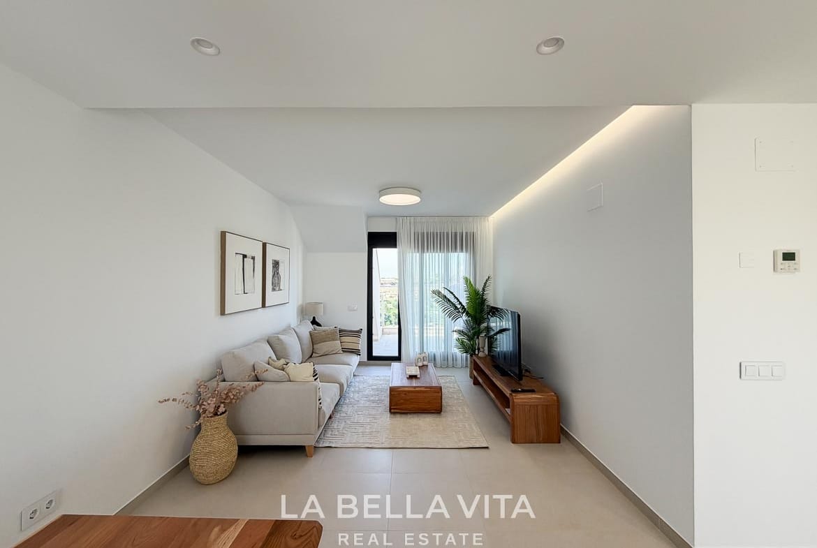 Long view of the lounge with neutral furnishings, concealed ceiling lighting and terrace access