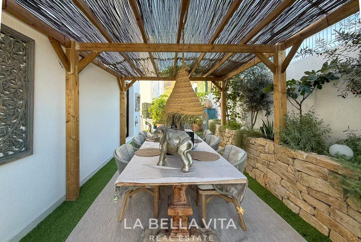 Outdoor dining table beneath a shaded pergola with a pendant light in Finestrat, Alicante.