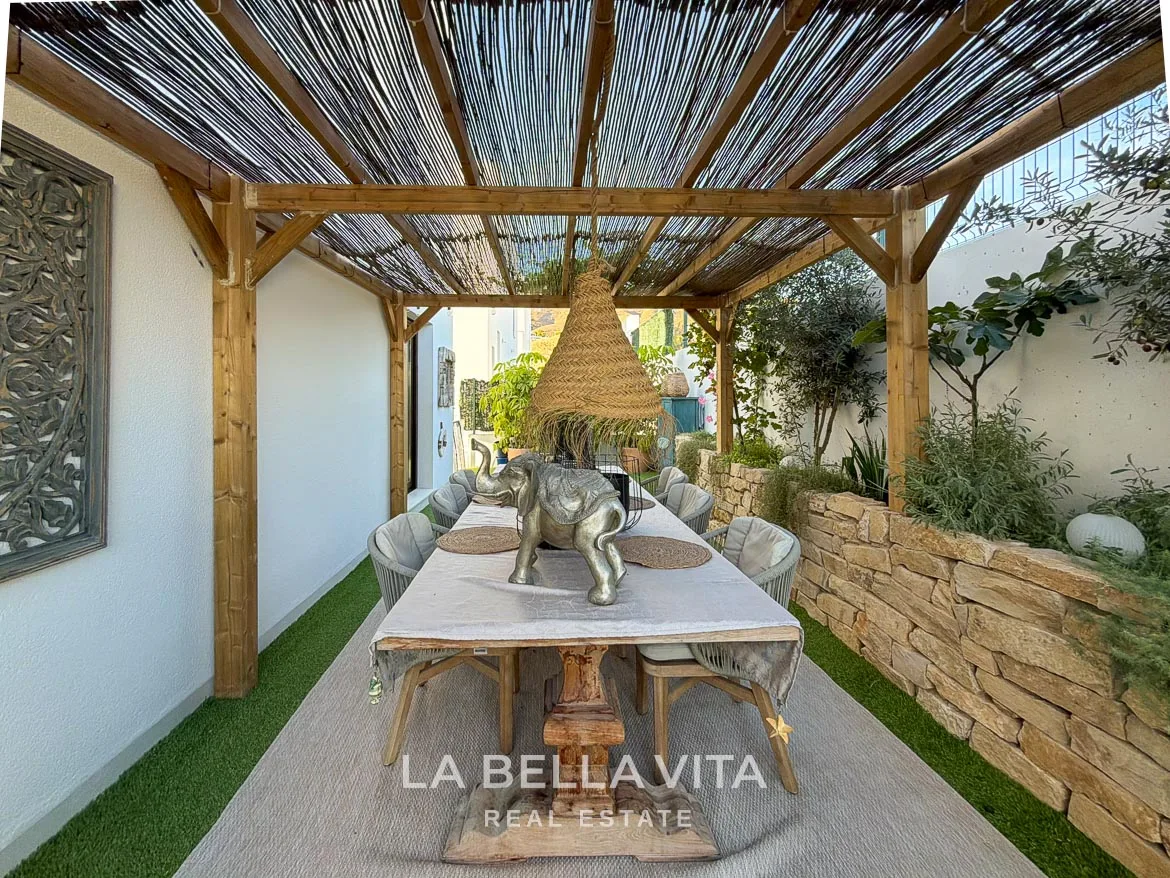Modern Resale Villa with Basement and Private Pool for Sale in Finestrat-10 Outdoor dining table beneath a shaded pergola with a pendant light in Finestrat, Alicante.