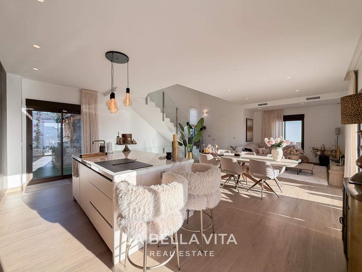Kitchen island with breakfast stools opening onto the dining area and glass staircase in Finestrat, Alicante.