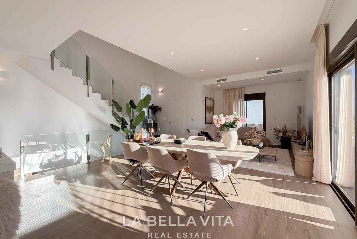 Open dining and living area beside a glass staircase and sliding terrace doors in Finestrat, Alicante.