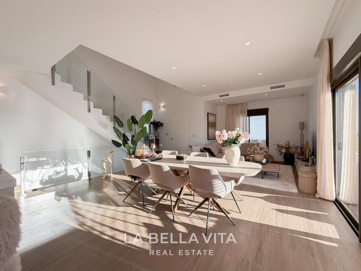 Modern Resale Villa with Basement and Private Pool for Sale in Finestrat-14 Open dining and living area beside a glass staircase and sliding terrace doors in Finestrat, Alicante.