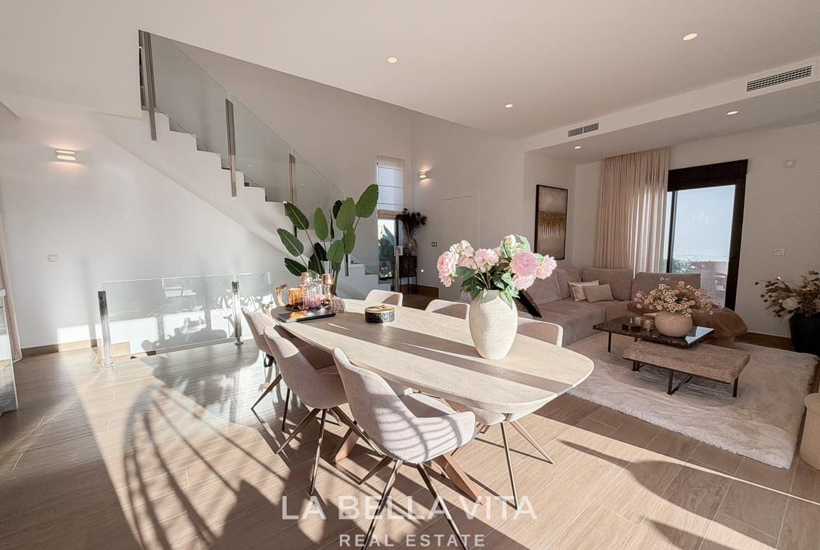 Dining table adjoining the lounge and glass-balustrade staircase in Finestrat, Alicante.