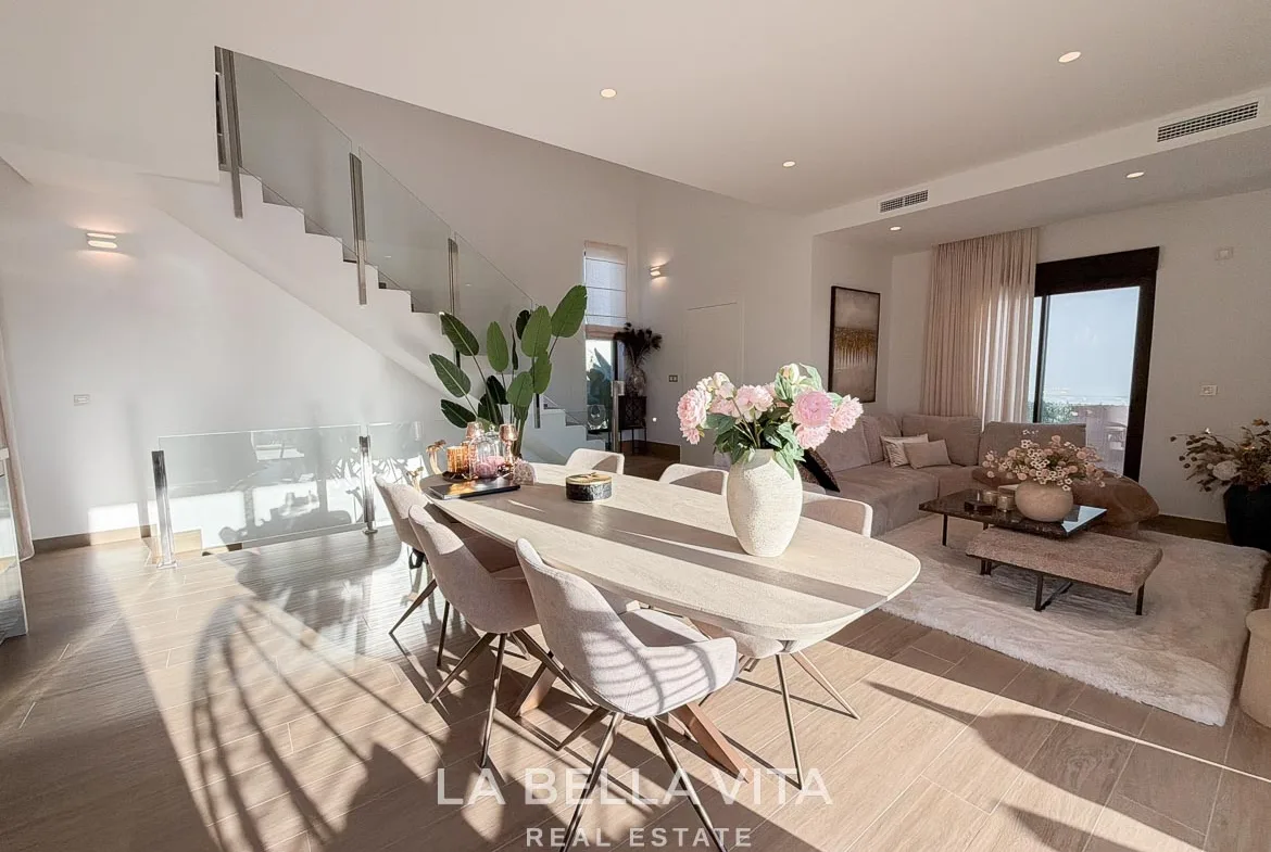 Dining table adjoining the lounge and glass-balustrade staircase in Finestrat, Alicante.