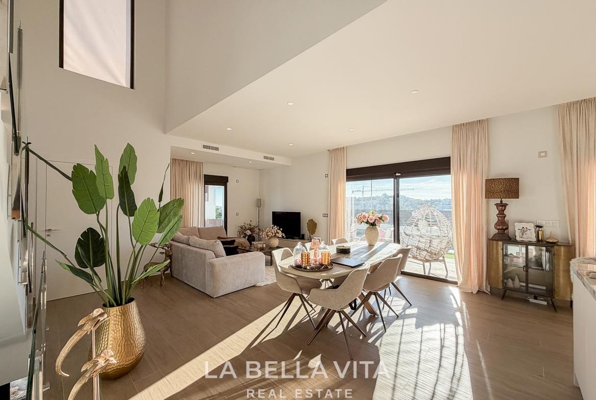 Open living and dining space with a tall stairwell window and terrace doors in Finestrat, Alicante.