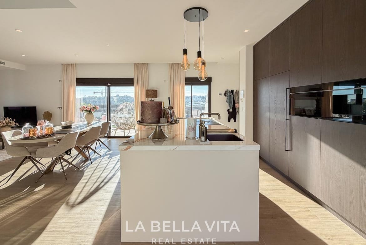 Kitchen island and wood-fronted cabinets with integrated ovens in Finestrat, Alicante.