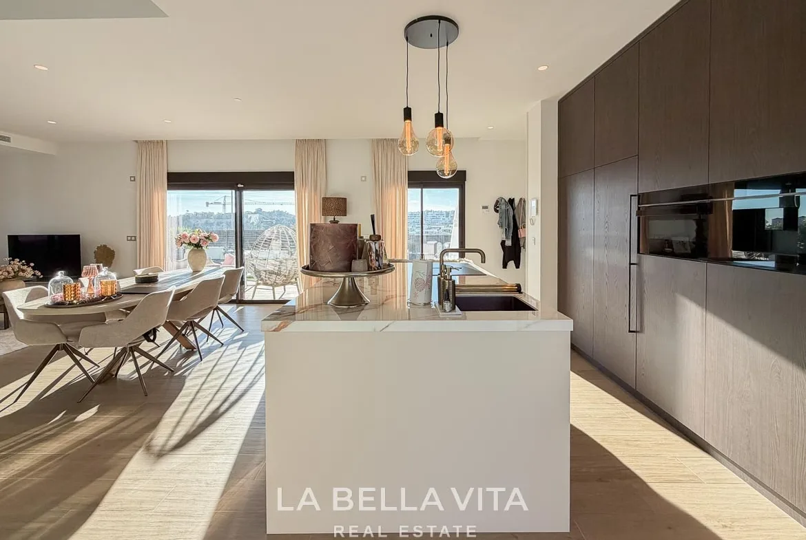 Kitchen island and wood-fronted cabinets with integrated ovens in Finestrat, Alicante.