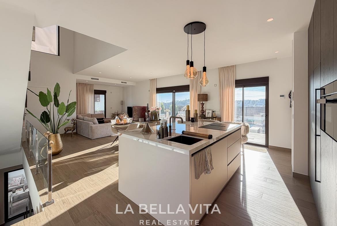 Kitchen island with sink and hob overlooking the staircase and dining area in Finestrat, Alicante.