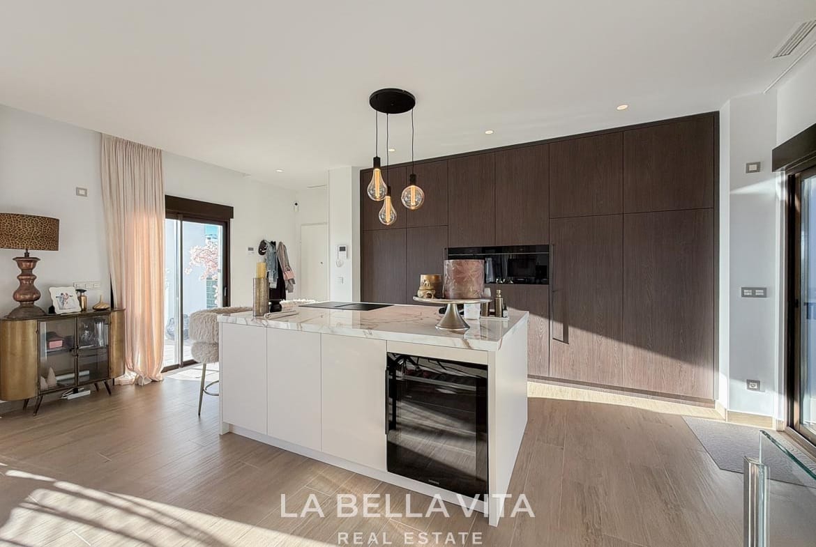 Kitchen island with a wine cooler beside wood-fronted cabinetry in Finestrat, Alicante.