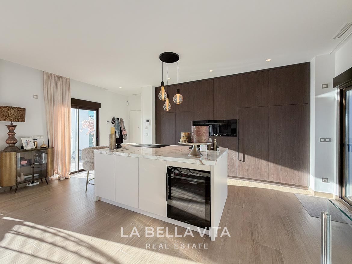 Modern Resale Villa with Basement and Private Pool for Sale in Finestrat-22 Kitchen island with a wine cooler beside wood-fronted cabinetry in Finestrat, Alicante.