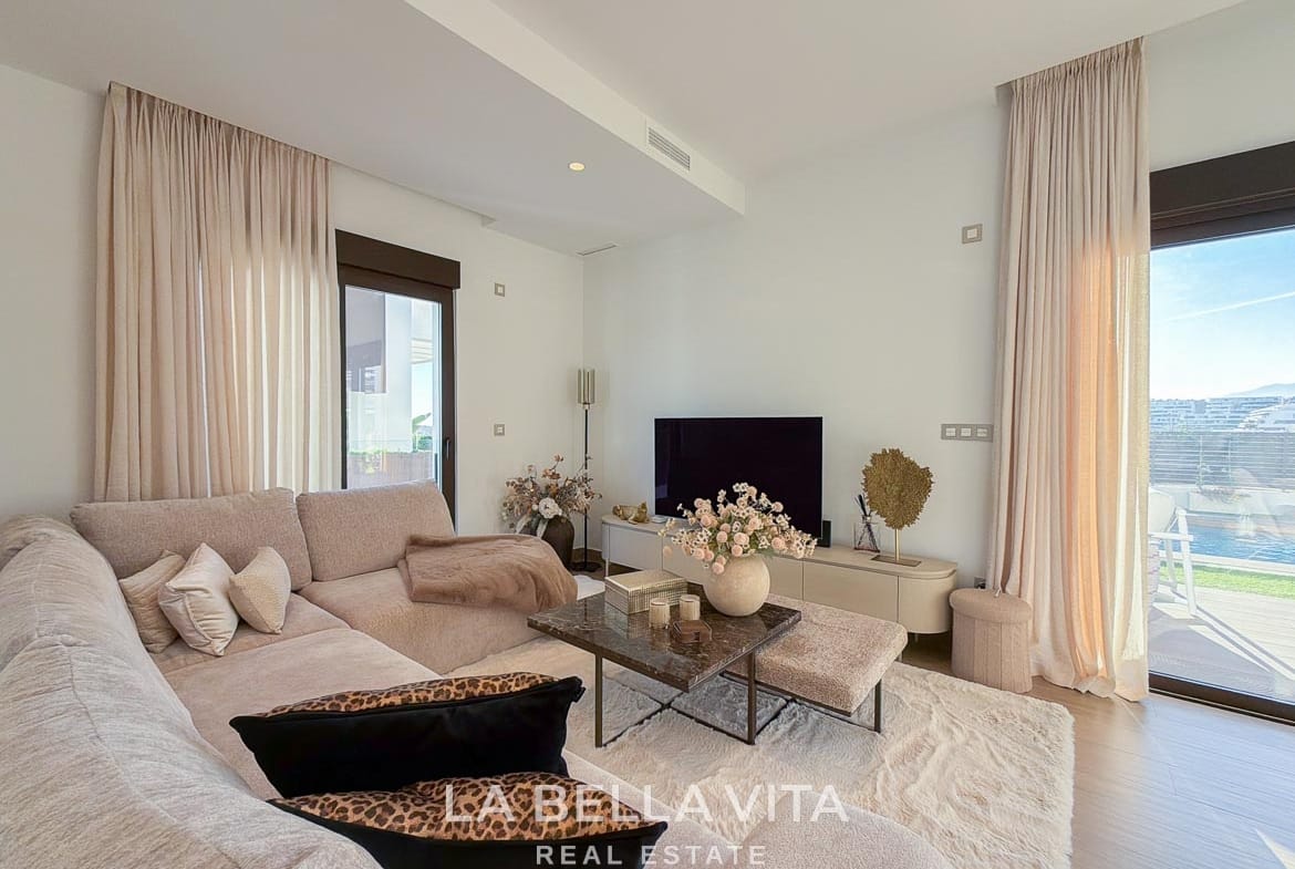 Living room with a corner sofa, coffee table, television and glazed terrace doors in Finestrat, Alicante.