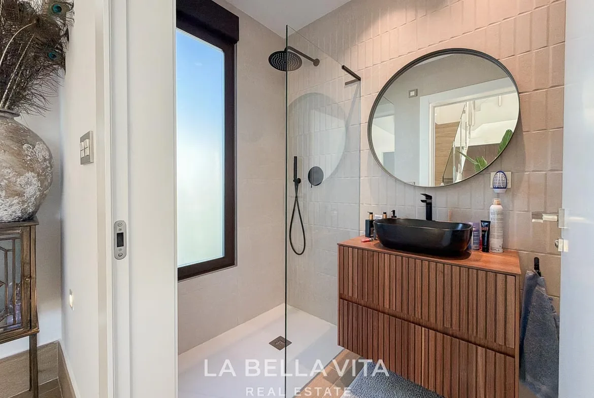 Shower room with a black basin, wooden vanity and round mirror in Finestrat, Alicante.