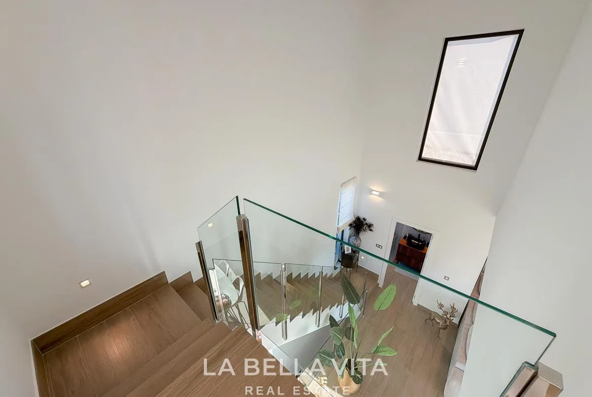 View down the staircase with glass balustrades and a tall window in Finestrat, Alicante.