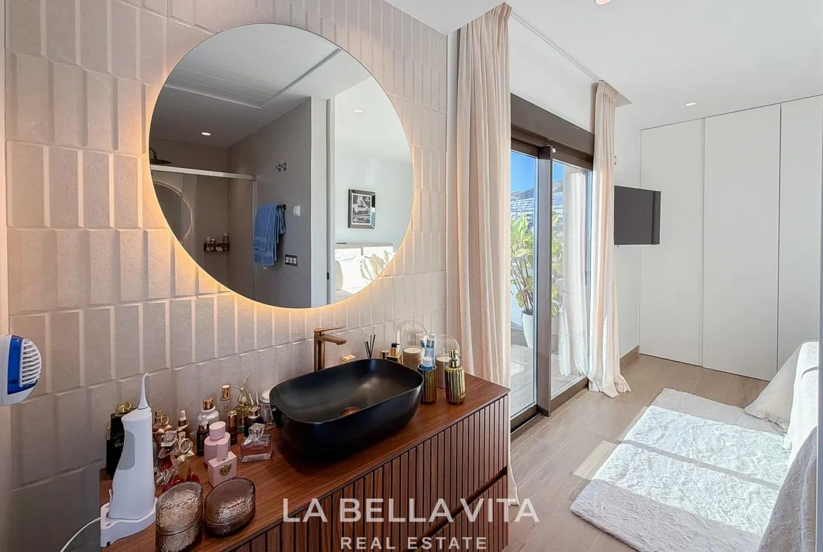 En-suite vanity with a black basin and illuminated mirror beside the bedroom in Finestrat, Alicante.