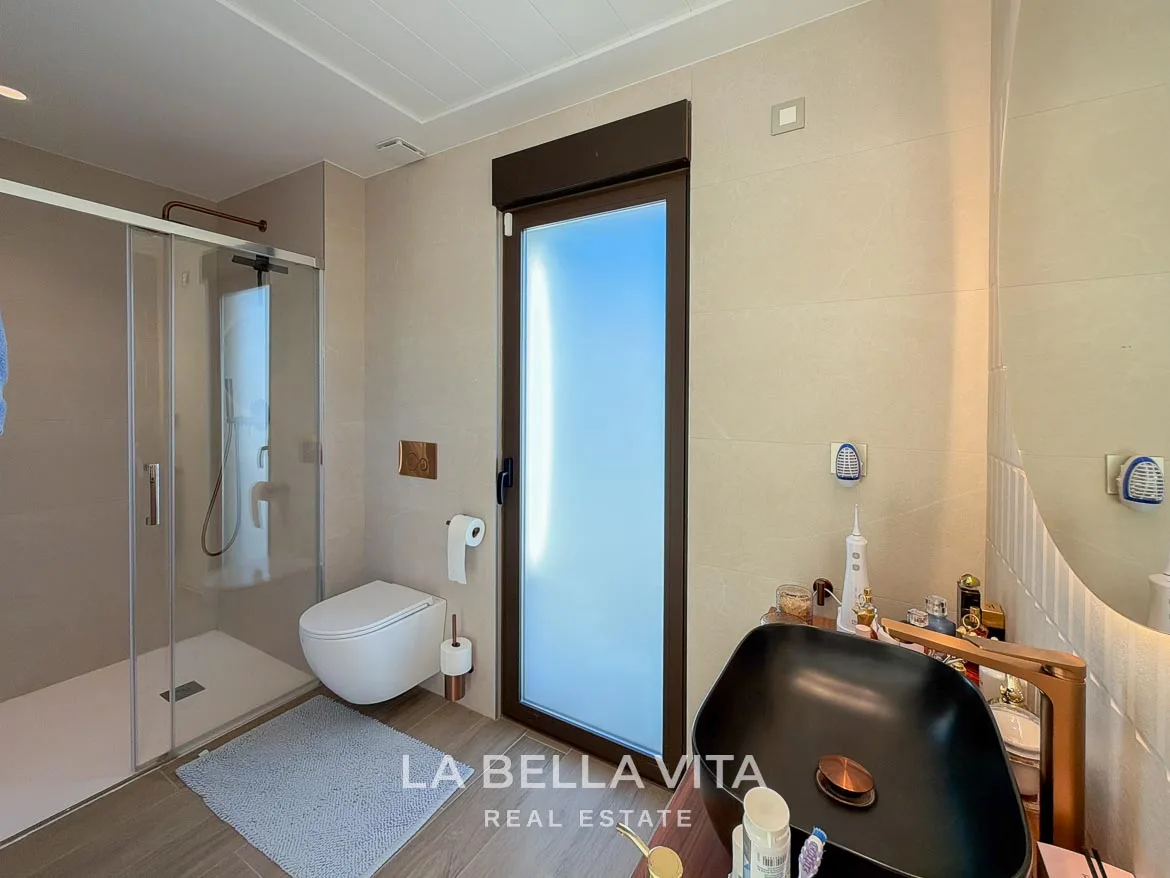 Modern Resale Villa with Basement and Private Pool for Sale in Finestrat-32 Bathroom with a glass shower enclosure, wall-hung toilet and tall frosted window in Finestrat, Alicante.