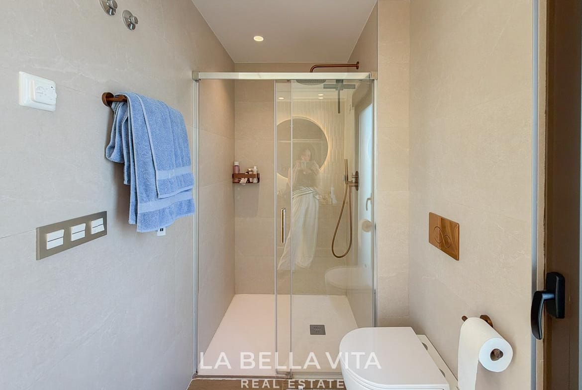 Glass shower enclosure and wall-hung toilet in the tiled bathroom in Finestrat, Alicante.