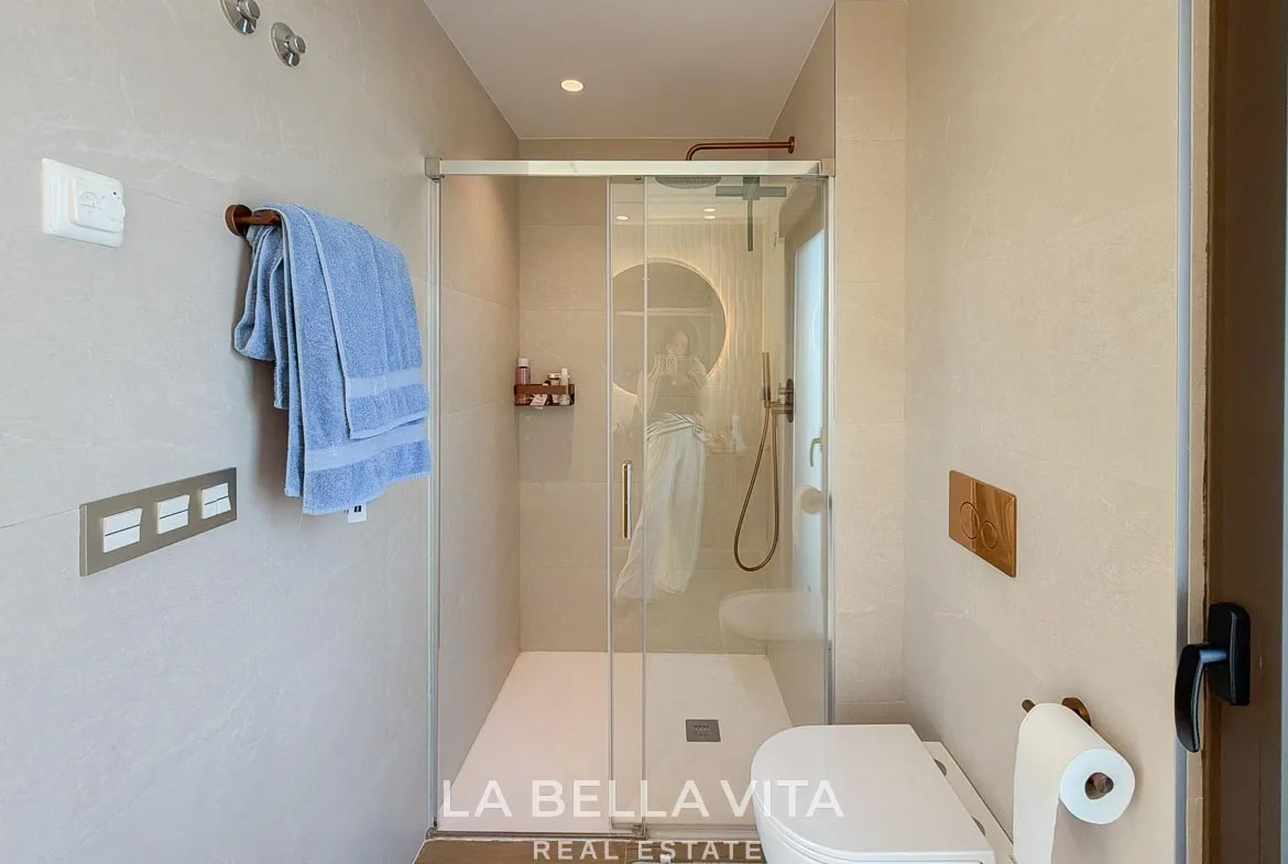 Glass shower enclosure and wall-hung toilet in the tiled bathroom in Finestrat, Alicante.
