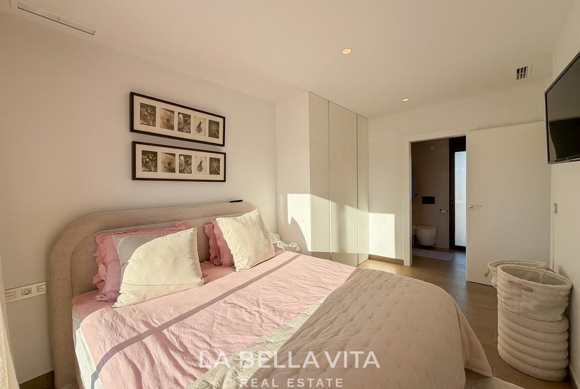 Double bedroom with fitted wardrobes and an open door to the en-suite bathroom in Finestrat, Alicante.