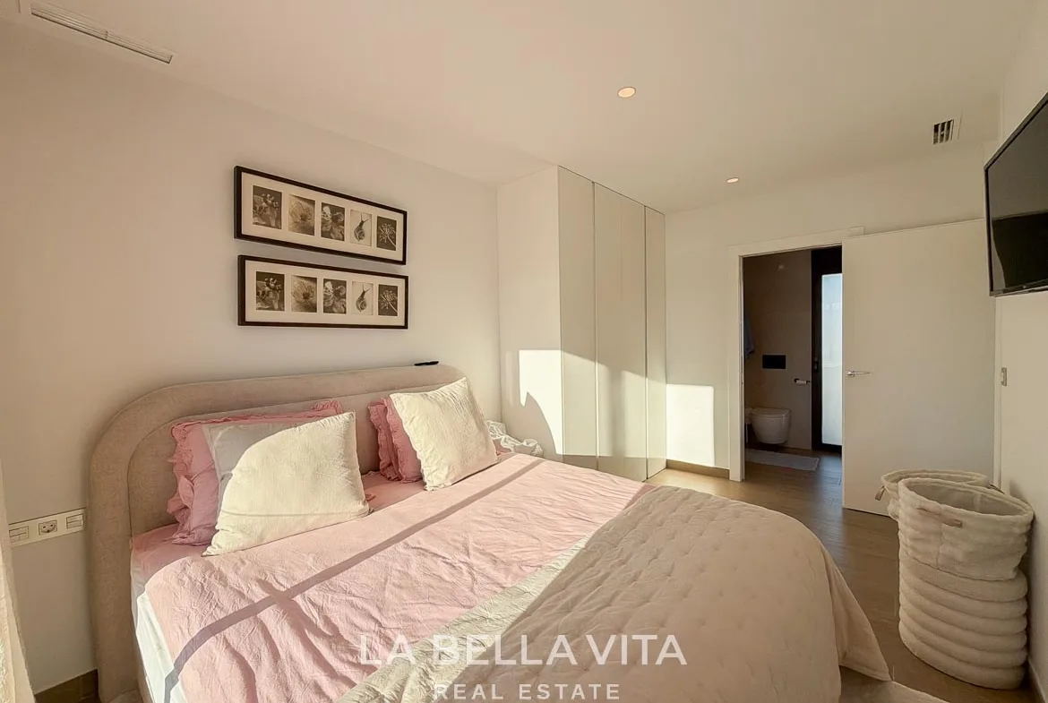 Double bedroom with fitted wardrobes and an open door to the en-suite bathroom in Finestrat, Alicante.