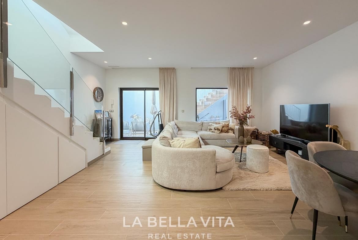 Basement lounge with a curved sofa and glazed doors opening onto the sunken patio in Finestrat, Alicante.