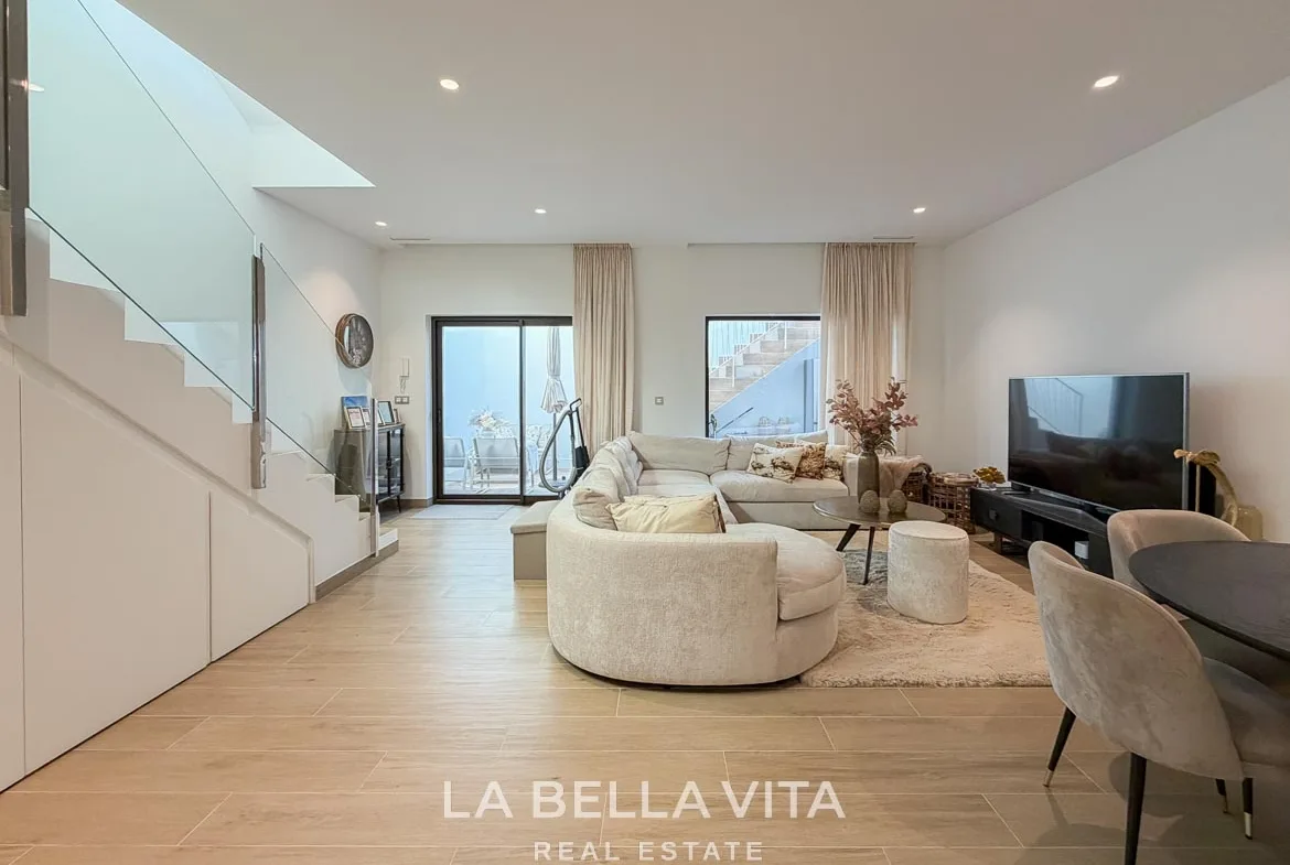 Basement lounge with a curved sofa and glazed doors opening onto the sunken patio in Finestrat, Alicante.