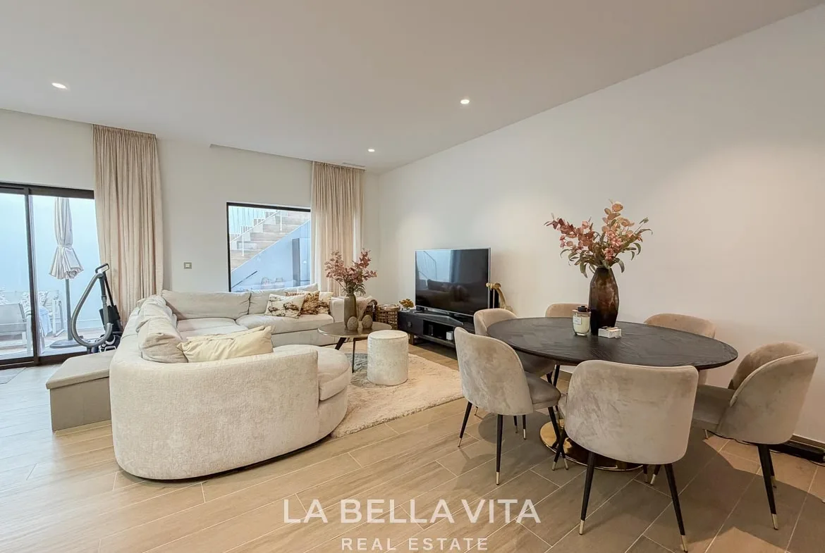 Basement dining table beside the curved sofa, television and patio doors in Finestrat, Alicante.
