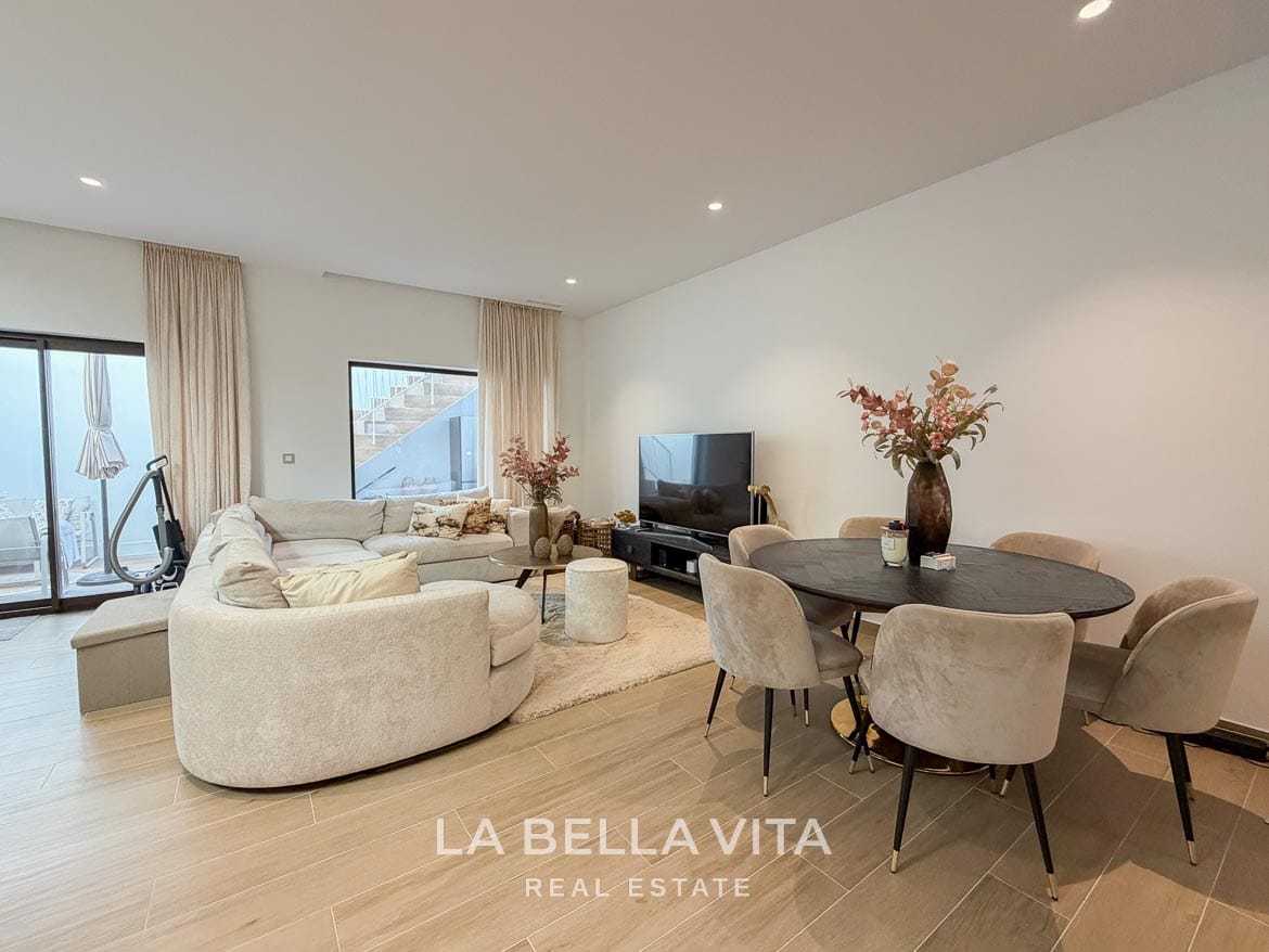 Modern Resale Villa with Basement and Private Pool for Sale in Finestrat-42 Basement dining table beside the curved sofa, television and patio doors in Finestrat, Alicante.