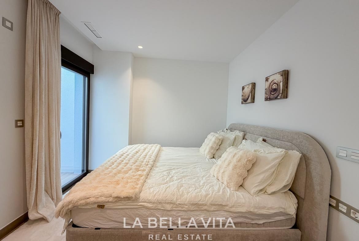 Double bed beside a tall glazed opening in the basement bedroom in Finestrat, Alicante.