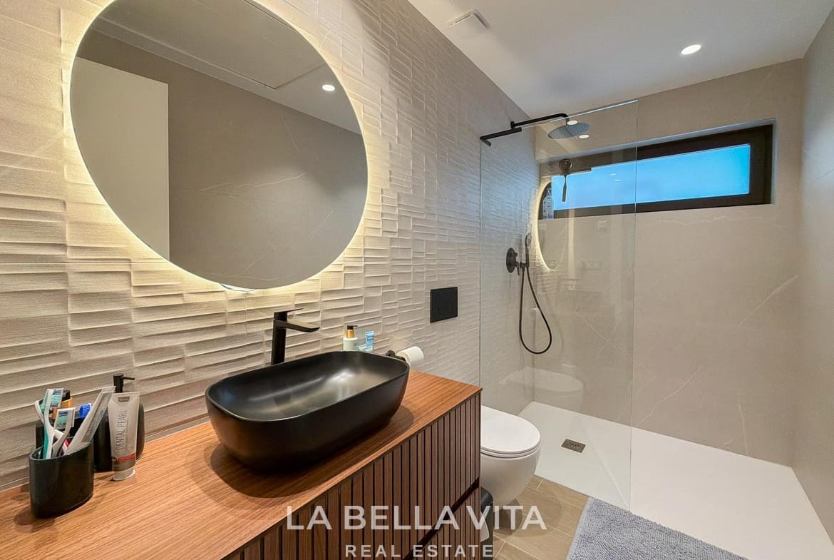 Basement bathroom with a black basin, illuminated mirror and glass shower screen in Finestrat, Alicante.