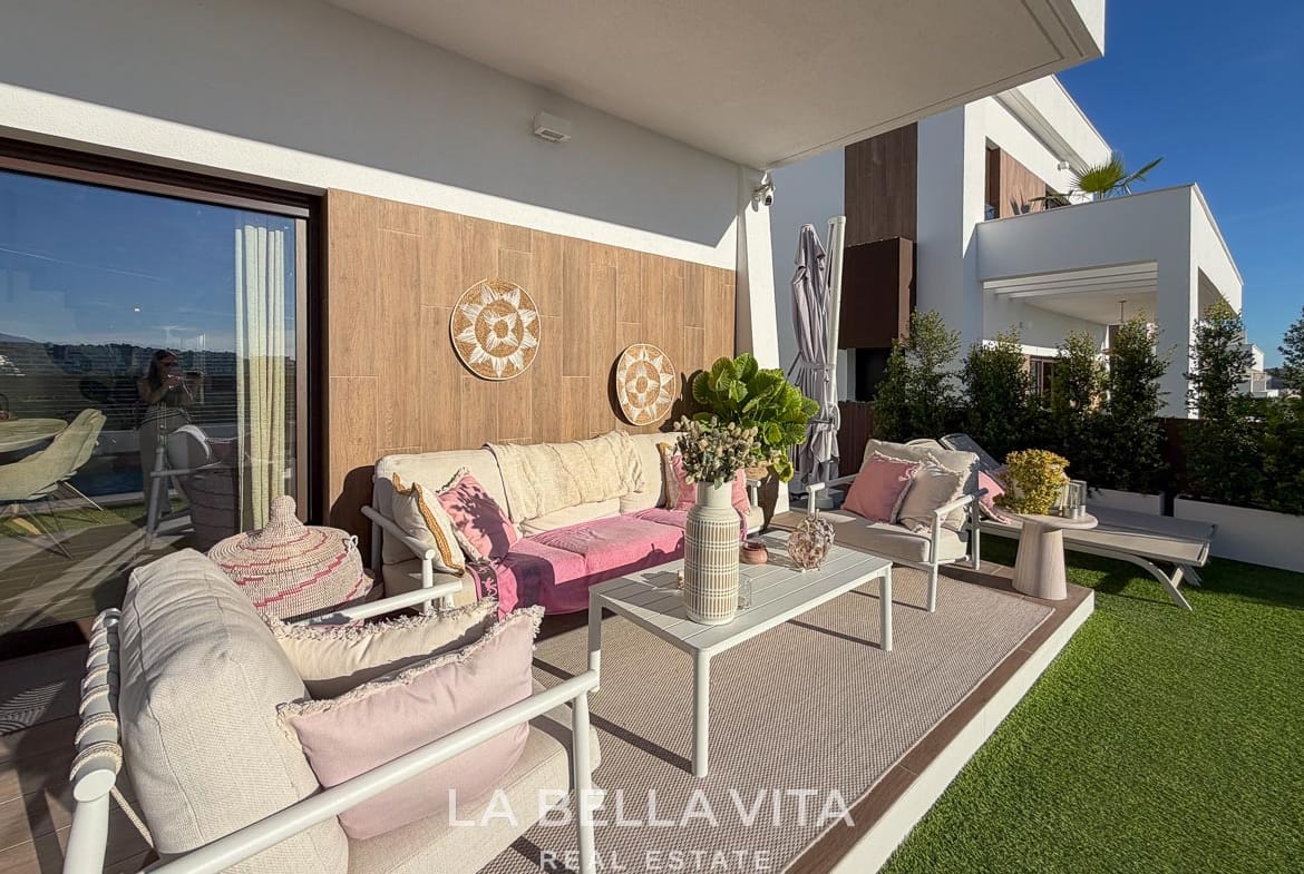 Covered outdoor seating area with a sofa, armchairs and pink cushions in Finestrat, Alicante.