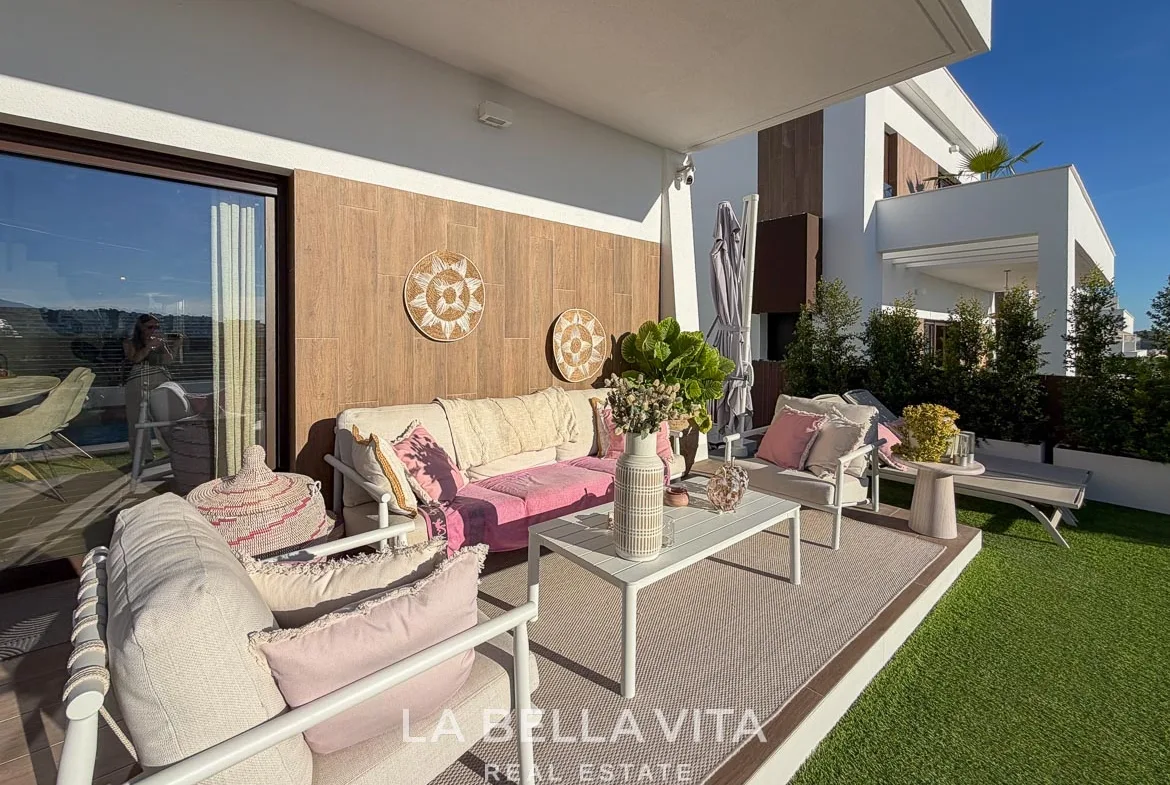 Covered outdoor seating area with a sofa, armchairs and pink cushions in Finestrat, Alicante.