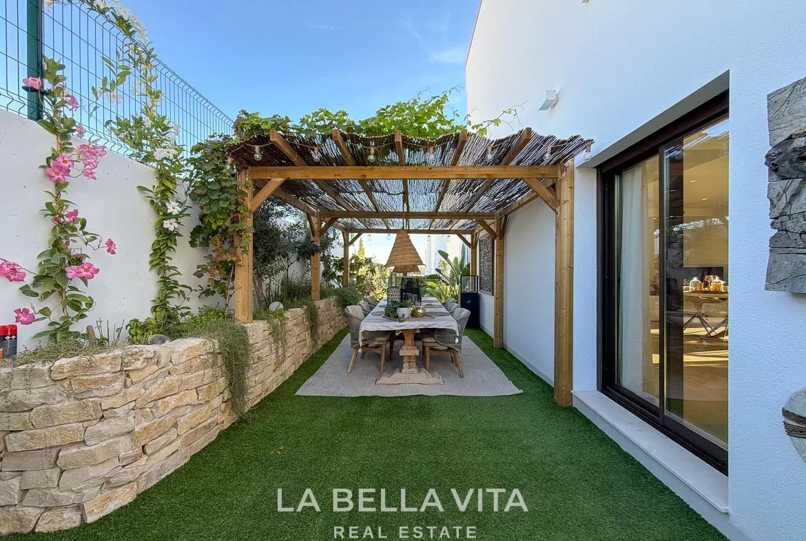 Garden dining area beneath a pergola beside stone planter walls in Finestrat, Alicante.